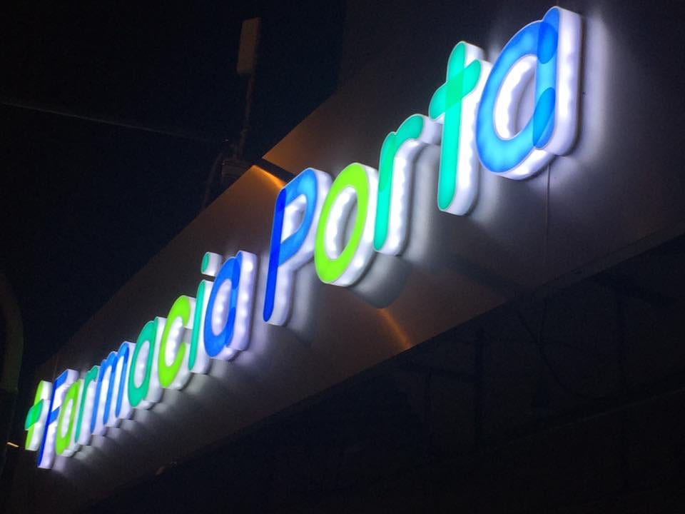 Frente de Farmacia Porta en Avenida Mitre 1390, Berazategui, de noche con el cartel iluminado